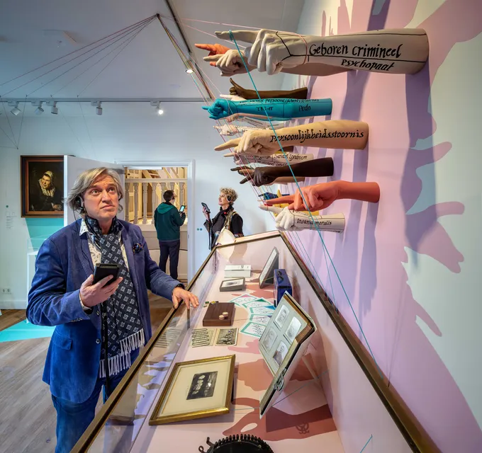 Plastic arms mounted on the wall in diverse colours, pointing at the visitors.