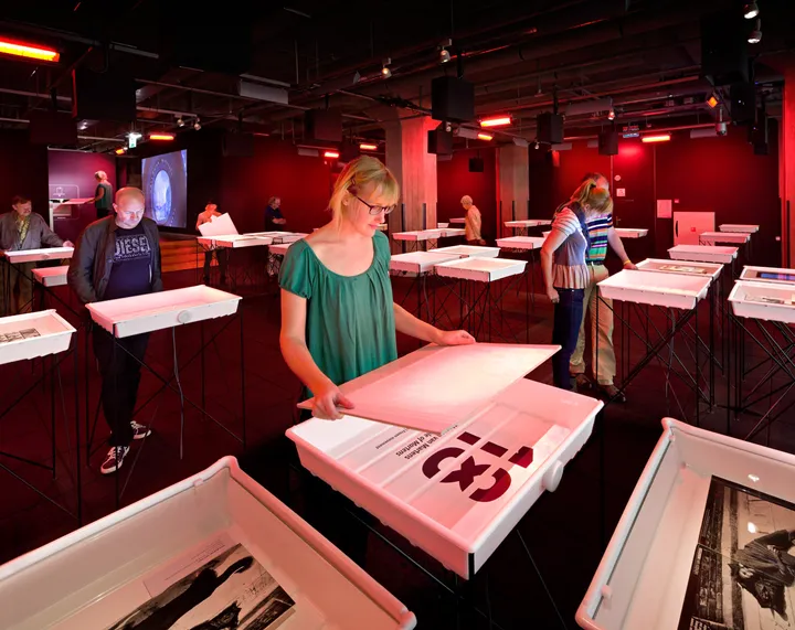 By putting a white sheet in a development tray, like in an old darkroom, the visitor activates the stories