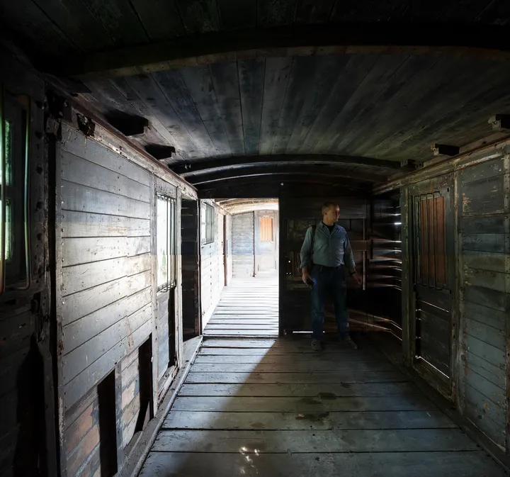 You step inside the empty, bare space of the freight wagon. There is minimal incidence of light and you are immersed in an intense audio experience.