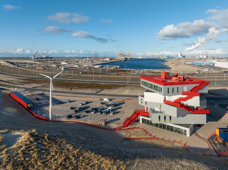 A red external staircase winds up along the building, leading visitors to the freely accessible panoramic deck, offering breathtaking views over the North Sea, the coastline, and the port.